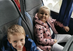 Dziewczynka i chłopiec pozują do zdjęcia w autokarze.