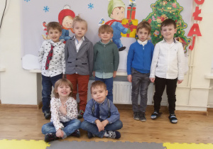 Widok na grupę chłopców pozujących do zdjęcia na tle bożonarodzeniowej dekoracji.