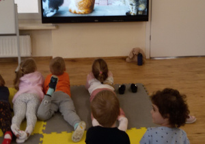 Widok na dzieci, które oglądają prezentację multimedialną o kotach.