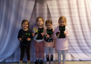 Cztery dziewczynki pozują do zdjęcia prezentując czarne koty.