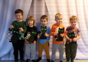 Pięciu chłopców pozuje do zdjęcia z papierowymi, czarnymi kotami.