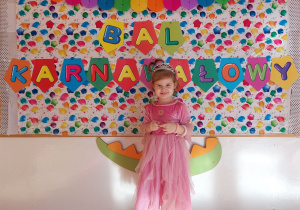 Dziewczynka w stroju księżniczki pozuje do zdjęcia na balu karnawałowym.