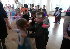 Dzieci tańczą tworząc pociąg w sali balowej.