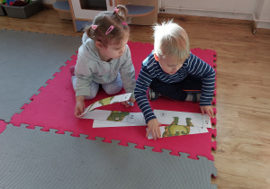 Chłopiec i dziewczynka układają z puzzli obrazek dinozaura.