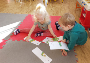 Chłopiec i dziewczynka układają z puzzli obrazek dinozaura.