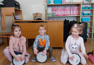 Zdjęcie chłopca i dwóch dziewczynek grających na bębnach.