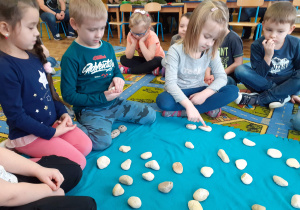 Dzieci grają w memory narosowane na kamieniach.