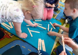 Dzieci łacza w pary drewniane patyczki na których są narysowane figury i cyfry.