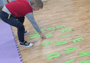 Chłopiec wybiera jedną literę z rozsypanego na podłodze zbioru liter.