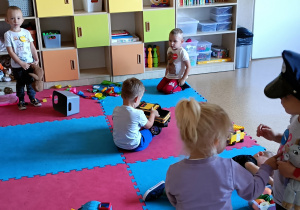 Widok na salę przedszkolną. Dzieci bawią się różnymi zabawkami.