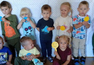 Dzieci pozują do zdjęcia (w tle materiał w kropki) trzymając w dłoniach kółko w kolorze żółtym, niebieskim.
