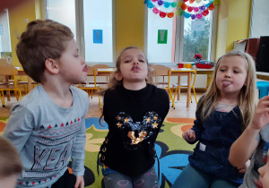 Dzieci dotykają na zmianę językiem do nosa i na brodę.