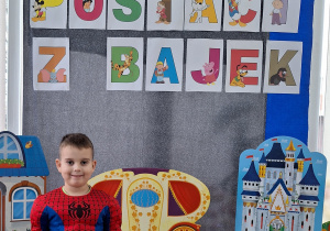 Chłopiec w stroju Spider-Man pozuje do zdjęcia. W tle znajduje się dekoracja z okazji Dnia Postaci z Bajek.
