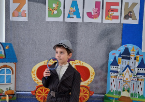 Chłopiec w stroju Inspektora Gadżeta pozuje do zdjęcia. W tle znajduje się dekoracja z okazji Dnia Postaci z Bajek.