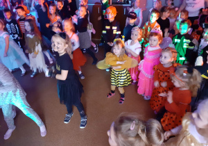 Dzieci w strojach karnawałowych tańczą.