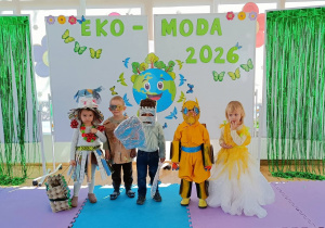 Widok na dzieci pozujące do zdjęcia w ekologicznych strojach, na tle dekoracji.
