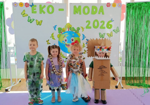 Widok na dzieci pozujące do zdjęcia w ekologicznych strojach, na tle dekoracji.