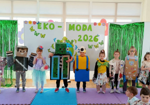 Widok na dzieci pozujące do zdjęcia w ekologicznych strojach, na tle dekoracji.