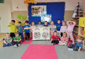 Widok na dzieci pozujące z przygotowanym plakatem, na którym przedstawiły zdrowe i niezdrowe produkty spożywcze.