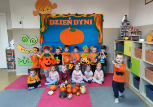 Widok na dzieci pozujące do zdjęcia, na tle jesiennej dekoracji przygotowanej z okazji Dnia Dyni.