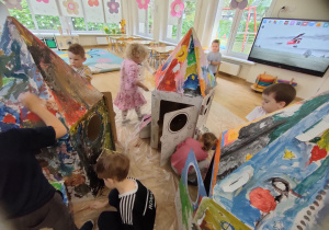 Widok na dzieci malujące tekturową rakietę 3D.