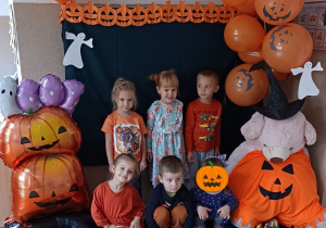 Widok na dzieci pozujące do zdjęcia na tle dekoracji.