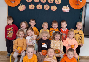 Widok na dzieci pozujące do zdjęcia, na tle jesiennej dekoracji przygotowanej z okazji Dnia Dyni.