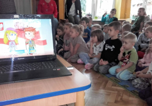 Dzieci z zainteresowaniem oglądają prezentację o symbolach Polski.