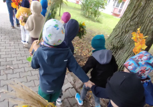 Widok na dzieci oraz Panie uczestniczące w jesiennym przemarszu ulicami miasta.