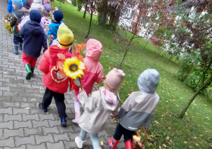 Widok na dzieci oraz Panie uczestniczące w jesiennym przemarszu ulicami miasta.