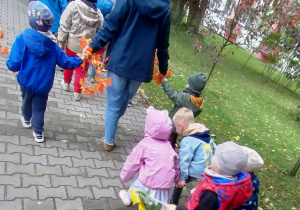 Widok na dzieci oraz Panie uczestniczące w jesiennym przemarszu ulicami miasta.