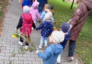 Widok na dzieci oraz Panie uczestniczące w jesiennym przemarszu ulicami miasta.