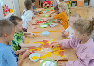 Widok na dzieci wyklejające kontur liścia.