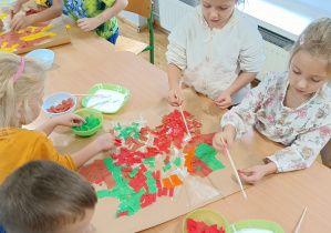 Widok na dzieci wyklejające kontur liścia.