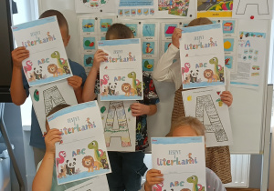 Widok na dzieci pozujące z zeszytem literkowym.