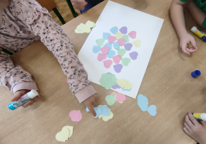 Widok na dzieci, które tworzą kształt serca za pomocą serc papierowych.