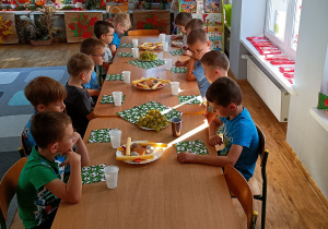 Widok na chłopców siedzących przy stole i świętujących "Dzień Chłopaka".