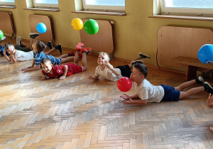 Widok na dzieci leżące i trzymające w dłoniach piłkę.