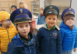 Widok na trójkę chłopców pozujących do zdjęcia w czapkach listonosza.