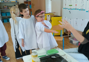 Widok na dzieci stojące jeden za drugim, czekające na wykonanie ekesperymentu "ogień na dłoni"