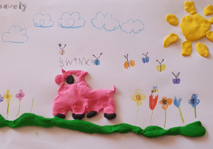 „Zwierzęta domowe”- praca wykonana przez Ksawerego. Przedstawia świnkę, która biega po zielonej trawie, nad nią napis świnka, wokół rosną kolorowe kwiaty, nad nimi fruwają motyle, w górze płyną chmurki, a w prawym, górnym rogu świeci ulepione z plasteliny słoneczko.