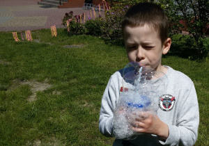 Chłopiec puszcza bańki mydlane.
