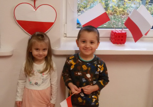 Nadia i Olek stoją na tle biało-czerwonych chorągiewek.