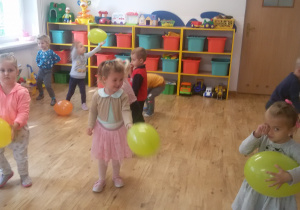 Grupa dzieci bawi się kolorowymi balonami.