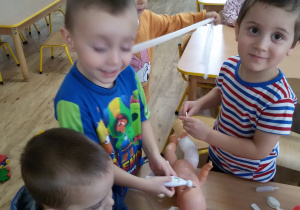 Widok na dzieci udzielające pomocy lekarskiej lalce.