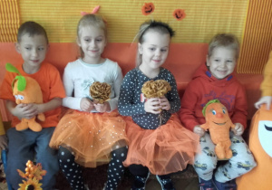 Dzieci w pomarańczowych ubraniach pozują do zdjęcia na pomarańćzowym tle.
