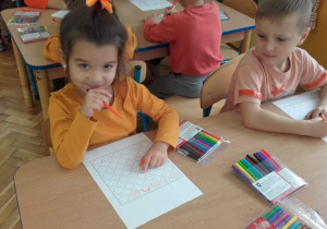Dzieci ozdabiają kwadrat pomarańczowymi wzorami